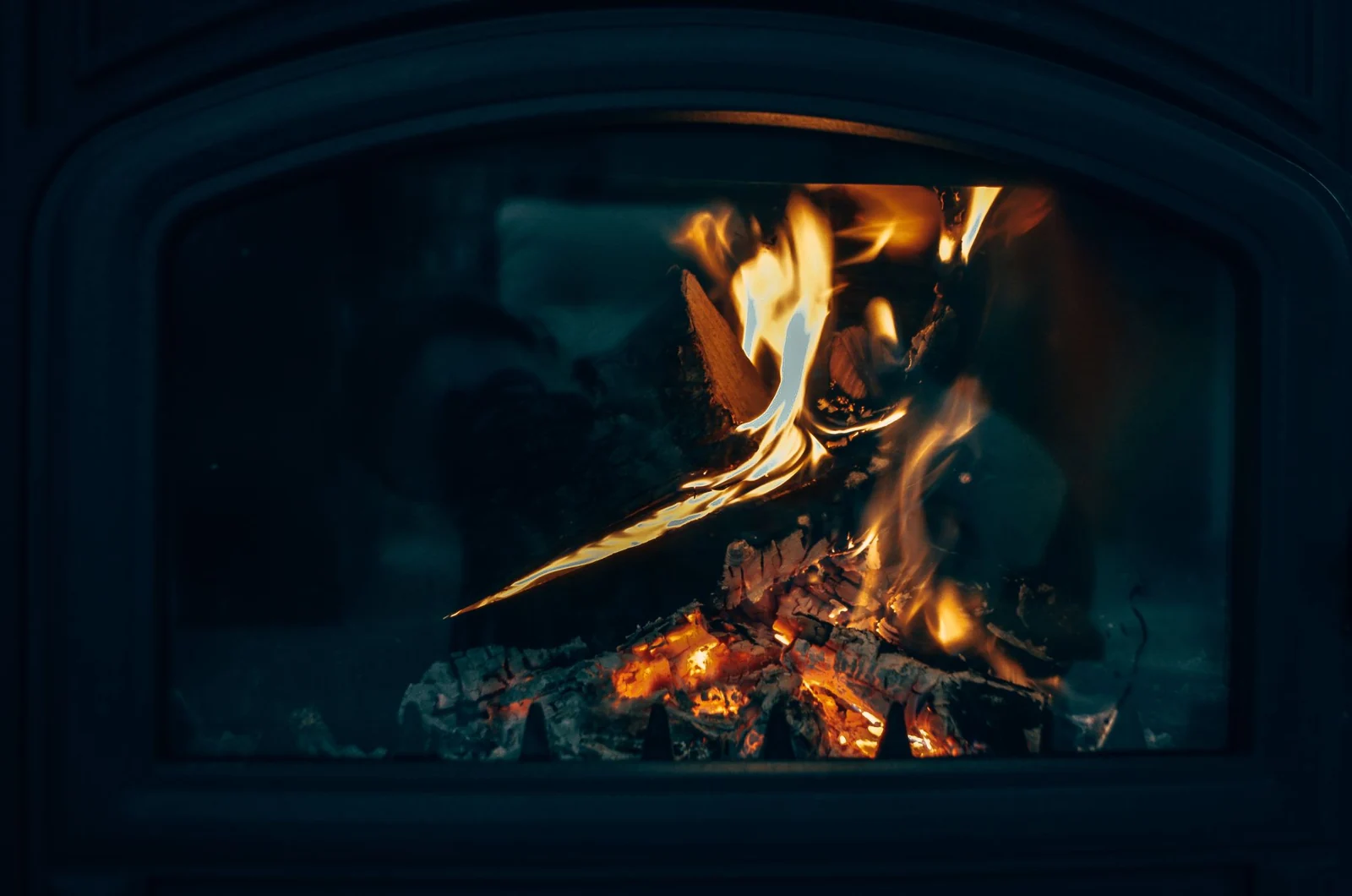 Burning wood beneath the dark arch of a firebox